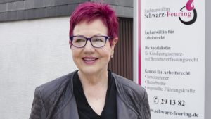 Frau Schwarz-Feuring steht vor Ihrem Kanzleischild.